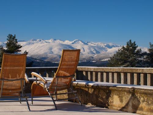 three chairs sitting on a balcony with mountains in the background at Parador de Gredos in Navarredonda de Gredos