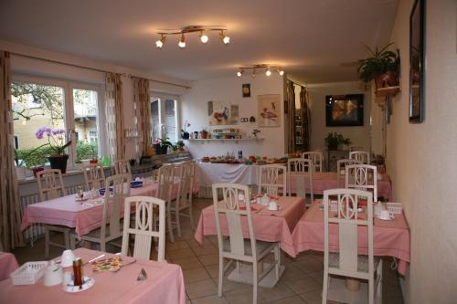 バートライヘンハルにあるホテル アルペンローゼのピンクのテーブルと椅子が備わるレストラン