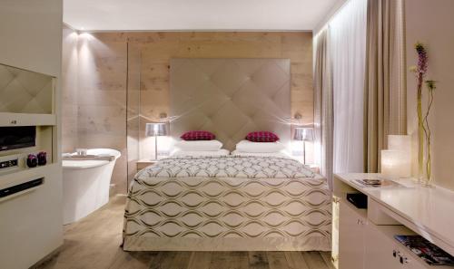 a bedroom with a bed and a tub and a sink at Giardino Mountain in St. Moritz