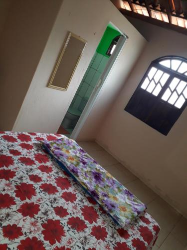 a bedroom with a bed with a flowered blanket and a window at Casa da Ú in Lençóis