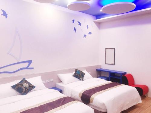 two beds in a room with birds on the wall at Purple Shell Homestay II in Magong