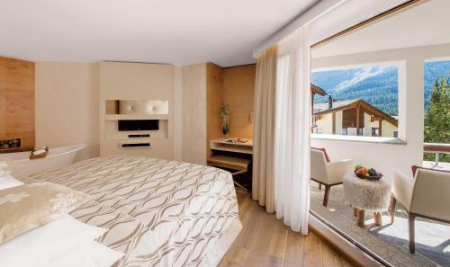 a bedroom with a bed and a large window at Giardino Mountain in St. Moritz