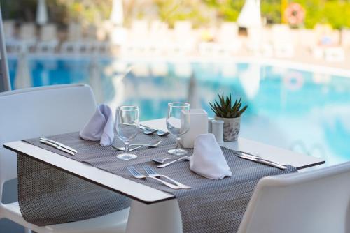a table with glasses and napkins on a table near a pool at Iberostar Waves Bouganville Playa in Adeje