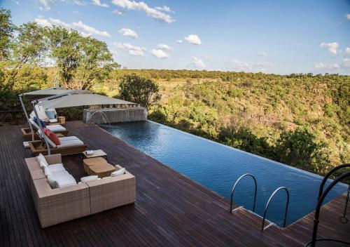 a pool with chairs and an umbrella on a deck at Moledi Gorge in Rustenburg