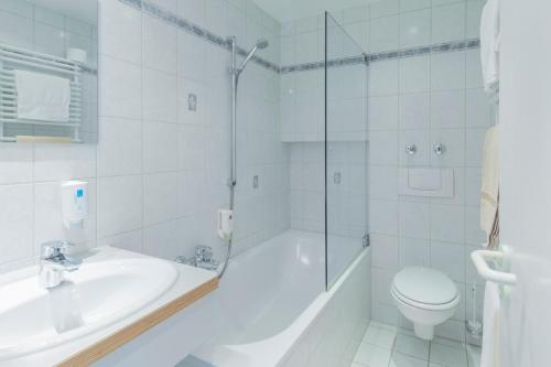 a white bathroom with a tub and a sink and a toilet at Hotel Riegeler Hof in Riegel