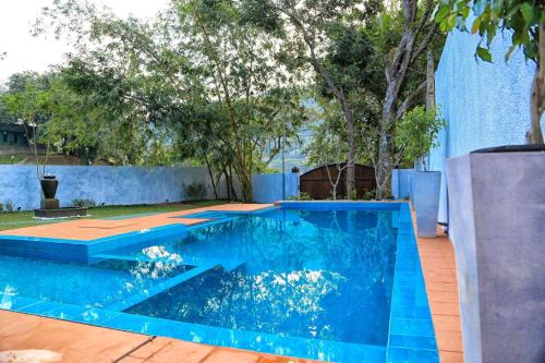 a blue swimming pool with a wooden floor and trees at Villa Kandy in Kandy