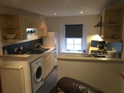 a kitchen with a washing machine and a window at Old Fisherman's Cottage in Rothesay