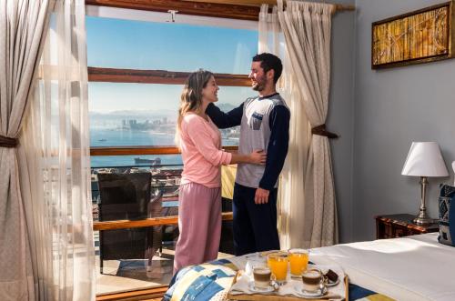 a man and woman standing next to each other in front of a window at Hotel Boutique Acontraluz in Valparaíso