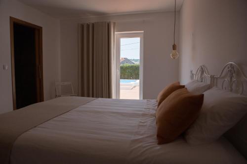 a bedroom with a white bed with a view of a pool at Casa dos Junqueiros - Countryside Guest House in Caldas da Rainha