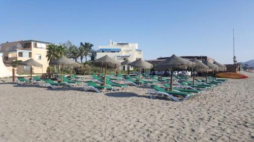 a row of lawn chairs and umbrellas on a beach at Apartment zona Naturista in Vera