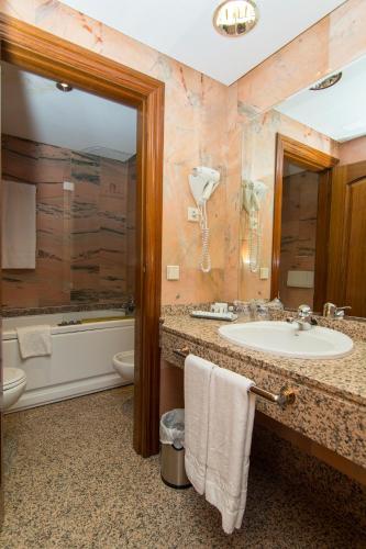 a bathroom with a sink and a tub and a toilet at Hotel San Antonio in Albacete
