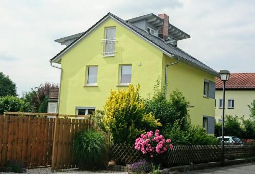 a yellow house with a fence and flowers at ApartmentHotel Vollumen in Redwitz an der Rodach