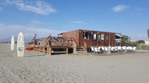 a house on the beach with chairs and a surfboard at Apartment zona Naturista in Vera