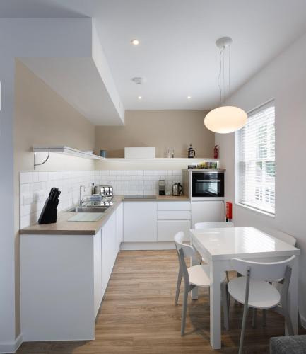 a kitchen with white cabinets and a table and chairs at Citystay Living - Devonshire Road in Cambridge