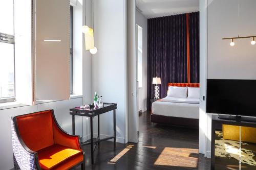 a room with a bed and a chair and a television at Hotel St Paul in Montréal