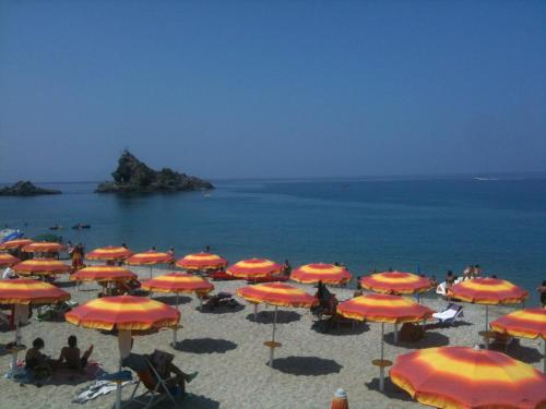 a group of umbrellas on a beach with the ocean at La Tonnara B&B in Palmi