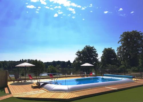 a large swimming pool with chairs and umbrellas at Camping Aquarev in Loudéac