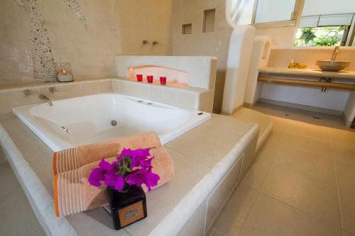 La salle de bains est pourvue d'une baignoire avec des fleurs violettes. dans l'établissement Villas Naomi, à Zihuatanejo