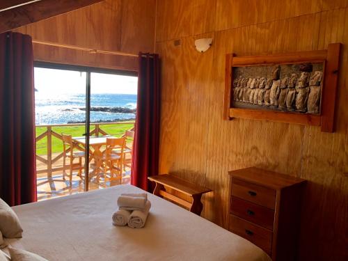 a bedroom with a bed with a view of the ocean at Cabañas Anavai Rapa Nui in Hanga Roa