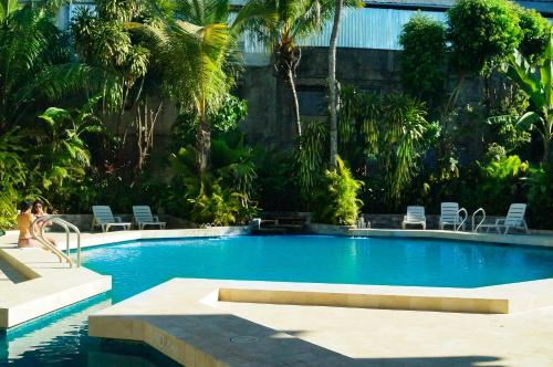 a woman is sitting next to a swimming pool at Grand Hotel Mercedes in Pucallpa