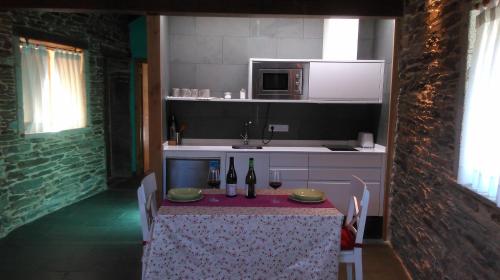 una cocina con mesa y 2 botellas de vino en Casa Do Grilo en Monfero