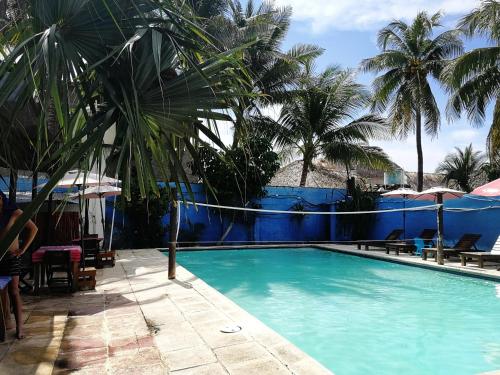 a swimming pool with blue walls and palm trees at Hotel El Delfin in Monterrico