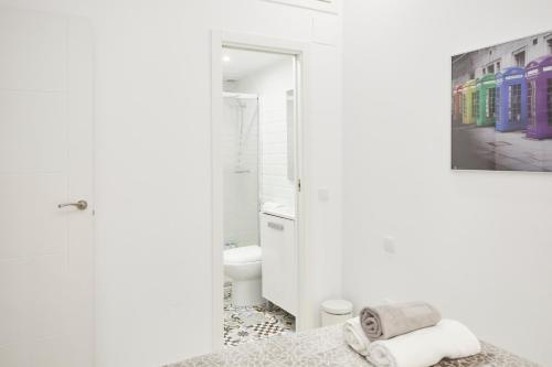 マドリードにあるLEEWAYS APARTMENT in DIVINO PASTORの白いバスルーム(ベッド1台付)が備わります。壁に絵画が飾られています。