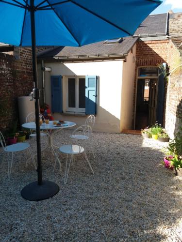 un patio avec une table, des chaises et un parasol dans l'établissement Chez Louise, à Guise