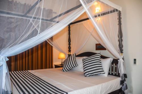 ein Schlafzimmer mit einem Himmelbett mit schwarzen und weißen Kissen in der Unterkunft Janu Homestay in Tangalle