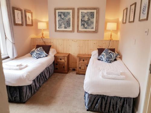 two beds in a small room with two lamps at The Red Lion in Kilsby
