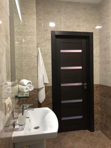 a bathroom with a white sink and a black door at Kechkemet Hotel in Simferopol