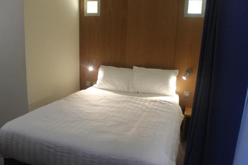 a bed with white sheets and pillows in a room at Corona Hotel Rotherham Sheffield Meadowhall in Rotherham
