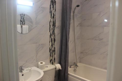 a bathroom with a sink and a toilet and a tub at Corona Hotel Rotherham Sheffield Meadowhall in Rotherham