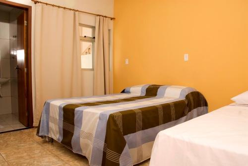 two beds in a room with yellow walls at Orquídea Hotel in Viçosa