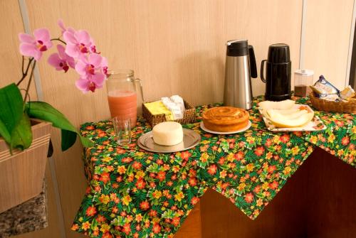 uma mesa com uma toalha de mesa com panquecas e uma bebida em Orquídea Hotel em Viçosa