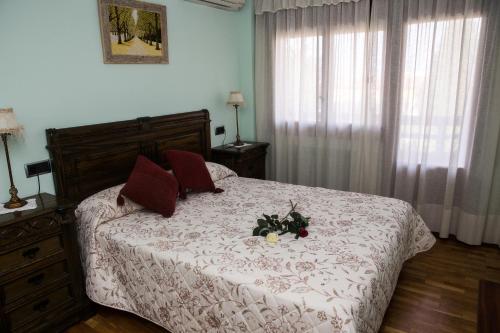 1 dormitorio con cama con edredón blanco y almohadas rojas en Finca Lebrel, en Pedrola