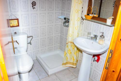 a white bathroom with a toilet and a sink at Mylos in Arkochórion