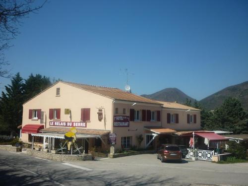 a building with a car parked in front of it at Logis Hotel Le Relais du Serre in Dieulefit
