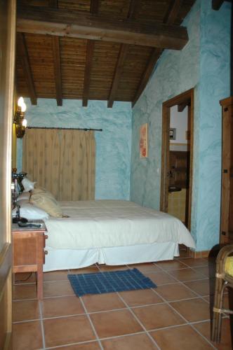 a bedroom with a bed in a room with blue walls at Casa Rural El Pedroso in Villar del Pedroso