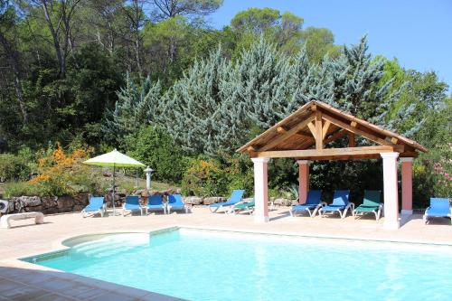 a swimming pool with a gazebo and chairs next to a swimming pool at Villa COLIBRI in Lorgues