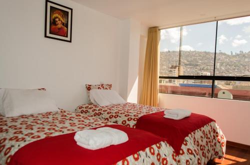 a hotel room with two beds and a window at Mayte Apartment in Cusco
