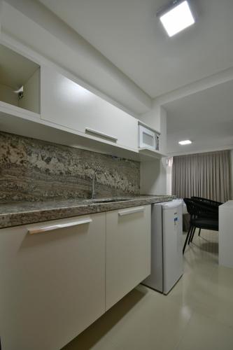 a white kitchen with a sink and a dishwasher at Littoral Gold Flat in João Pessoa