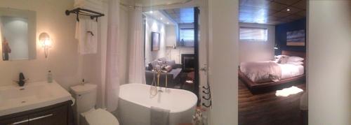 a bathroom with a sink and a toilet and a bed at Spa inspired guest suite in Jasper