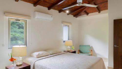 a white bedroom with a bed and a window at Town House 6 in Iguana