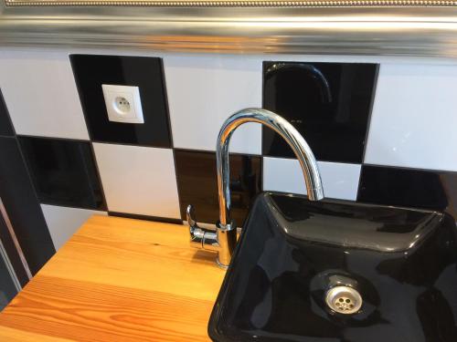 a black sink in a kitchen with black and white tiles at Artrooms in Poznań