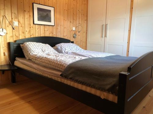 a bed in a bedroom with a wooden wall at Svenskveien 23b in Røros