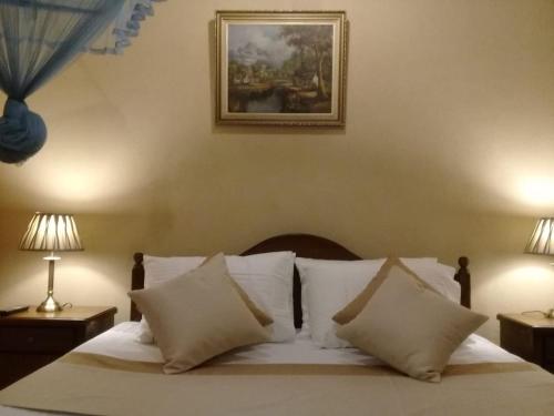 - un lit avec des oreillers blancs et une photo sur le mur dans l'établissement Avondale Colombo, à Maharagama