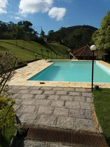 uma piscina com um passadiço de pedra ao redor em Canto da serrinha em Teresópolis