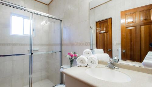 a bathroom with a sink and a shower with towels at Villas Iguana A-13 Beachfront Condo in Iguana