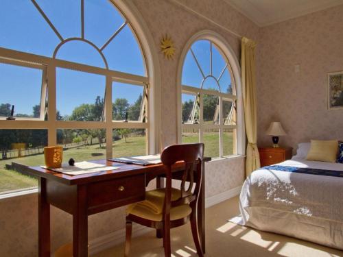 a bedroom with a desk and a bed and windows at Rua Resort in Hamilton